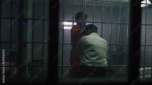 Criminal hits prison officer, takes keys, opens prison cell. Prisoner in orange uniform escapes from jail. Offender runs away from detention center or correctional facility. View through metal bars.