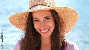 Embarrassed woman smiling at camera on the beach during summer