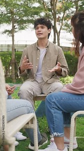 Asian group of people sit in a close circle and talk to therapist in park. Smile people sharing story happy speak diverse people in circle at group therapy session with psychologist. Vertical Screen.
