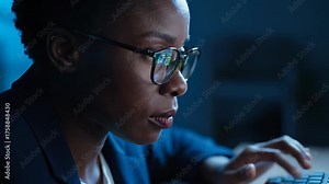 Woman types on laptop in office. Close up shows developer focused on computer monitor. Eyewear reflects lines of code on screen. Hands rest on keyboard during typing. Programmer works late focused.