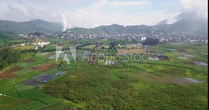 Backward Drone shot of rural landscape of Dieng Plateau with view of plantation, Arjuna Temple and settlement. The famous Cultural Village of Dieng Plateau called land of gods,Central Java, Indonesia
