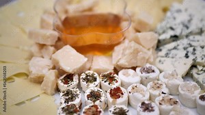 cheeses of different varieties are laid out on a dish and a plate with honey