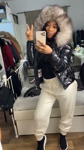 A shiny, glossy Moncler puffer puffy down jacket with a hood and white fur on the hood.