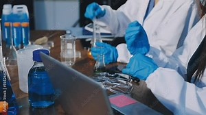 Technician holding blood tube test in the research laboratory / doctor hand taking a blood sample tube from a rack with machines of analysis in the lab background