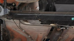 Cladding, frame and elements of the car's exhaust system. The camera pans along the bottom of the car mounted on the lift. The car's fuel system, exhaust pipe with muffler. 4k