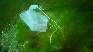 Plastic under water. A medical mask after the Covid-19 pandemic swims in the ocean. Environmental pollution. People Threw Out Medical Mask After End Pandemic Quarantine Epidemic