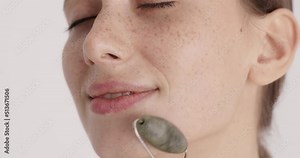 Woman smiling with closed eyes while using quartz face roller