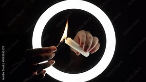 female hands light a candle close-up on a black background. burning fire on a candle stick. The concept of ritual actions