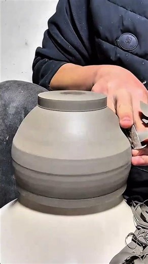 Trimming and refining the shape of a clay pot on a pottery wheel using a carving tool