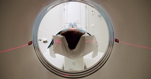Woman during CT scanning procedure. Tracking shot of female patient lying on table sliding into CT machine near crop doctor in laboratory of modern clinic.Modern technologies.Shot Of CT Scanning Room.