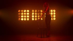 Girl performing strip dance in nightclub stage. Sexy woman walking seductive.