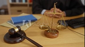 Judge sitting at desk with gavel scale keyboard and documents in courtroom