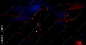Beautiful girl playing drums on stage during rock concert. Drummer girl makes beats with sticks on a metal Hi-Hat cymbal. Girl drummer concert concept. Camera getting closer to the girl
