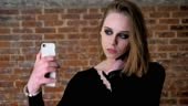 Young charming girl with smoky eyes make seifie on her smartphone,...