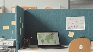 No people shot of opened laptop with world map on screen at office desk divided by partition walls