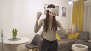 Fit young woman wearing VR headset swiping left and right with controllers playing games