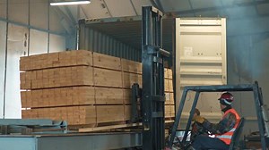 Forklift Loading Lumber Into Shipping Container Indoors