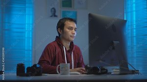 casual young Muslims Asian wearing red hoodie getting tired and sleepy when working from home at night in a modern interior design workspace with the warm blue light