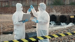 Ecologist sampling water from the river with test tube and save data to laptop computer, Biologist in a protective suit and mask collects sample of waste water from industrial, problem environment