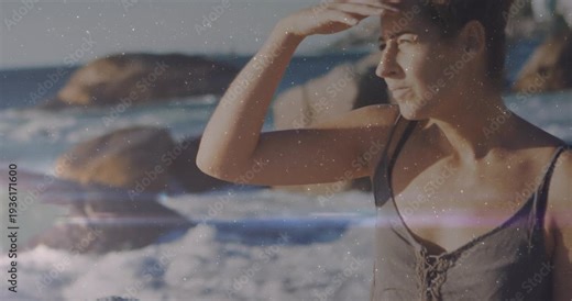 Woman on rock shading from sun, adjusting hair, scanning sea, flare crossing frame health