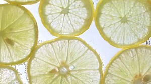 Download Juicy lemon slices with bubbles under water isolated on white background. Yellow lime slices pattern textured background. for free