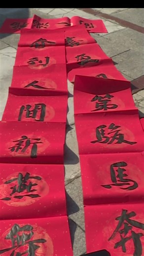 书法爱好者免费为畲族村民书写春联。Calligraphers write Spring Festival couplets for She ethnic villagers for free.