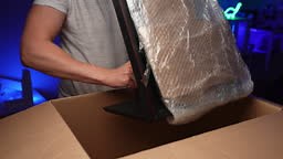 Gamer male unpacking cardboard box with new gaming monitor wrapped in...