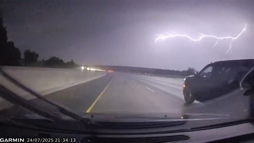 Sudden lightning bolt illuminates highway during storm in Guelph, Ontario