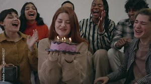 Excited young lady ready to blow out candles on cake on birthday party with happy friends. Happy birthday woman blowing out burning candle on cake with friends clapping hands, singing song together Stock Video