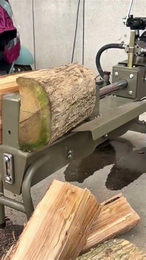 splitting large wooden logs into smaller pieces using a hydraulic log splitter machine for firewood