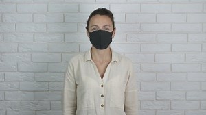 Delivery system in quarantine. A female in a personal mask hold a craft bag and cotton bag in her hands in the room.