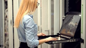Female IT technician using laptop in server room of data center