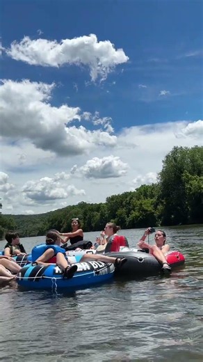 Ben catches a cherry in his mouth while tubing in the river