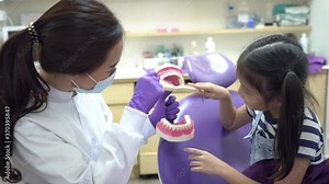 young asian dentist teach a girl to brush tooth in dental clinic