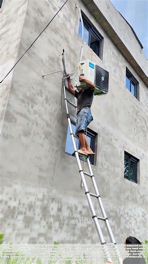 Balancing the Unit: How a Man Carries an AC Unit Up an Aluminum Ladder in Flip-Flops