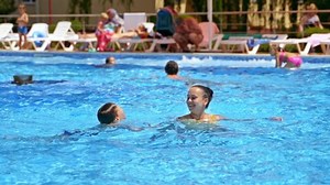Happy family in swimming pool. Children with mother on summer vacation in swimming pool