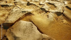 Dry, cracked desert floor made of fine sand, scattered with small rocks, representing the devastating effects of global warming and the shrinking water sources on Earth.