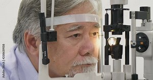 Doctor checking senior patients eyes with medical biomicroscope device.