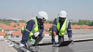 Professional engineer work to maintenance of photovoltaic panel system. Attractive technician worker working on roof inspect and check solar cell panels equipment box at solar cell field during sunset