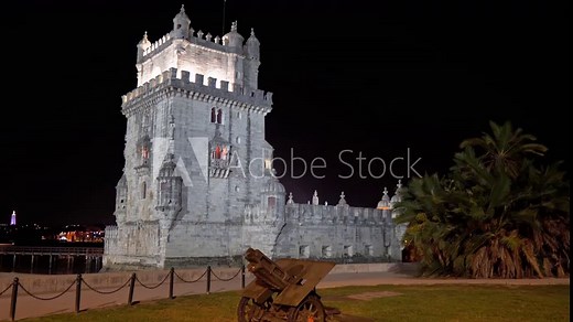 Iconic Belém Tower from the surrounding park at night with a historical cannon in the foreground in Lisbon, Portugal.