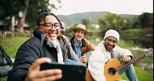 Forest, selfie and friends at lake with guitar, happy and enjoying music or camping in nature. Smartphone, profile picture and group of people relax in woods, fun and enjoy freedom at river with beer