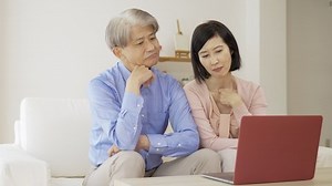 A middle-aged couple thinking while looking at a computer