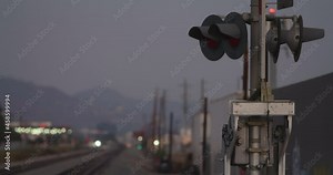 Railroad Tracks Intersection, Crossing Lights and Signs. Cars Drive Through Intersection. No Train, Sunset Or Dusk, Hills In Background