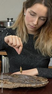 Woman using dowsing pendulum over big agate stone. Vertical video. Stock Video