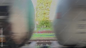 Freight train with tanks rushing past village. Cargo transport with cisterns filled with oil, fuel, gasoline and other industrial liquids. Locomotive moves by railroad crossing at countryside.