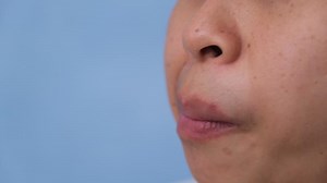 Download Young woman chewing gum and blowing bubble gum on blue background. for free