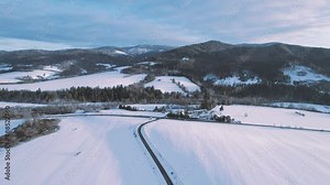 Scenic drone aerial view parallel to lonely road in middle of snowy mountain scenery in Slovakia, Banska Bystrica, Brezno