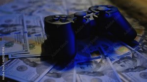 Game console joystick on hundred dollar bills, close-up. Profitability from participation in video games concept