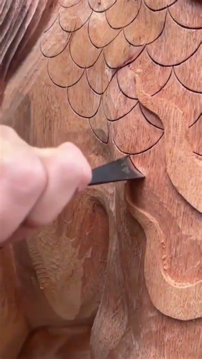 carving detailed dragon scale patterns on a wooden sculpture surface using a sharp metal chisel