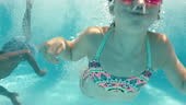 happy children jumping in swimming pool splashing underwater...